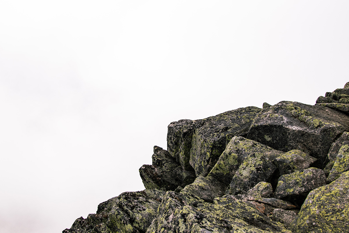 An outcropping of dark, jagged rocks with lichen.
